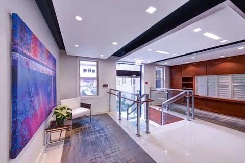 A hallway with a large painting on the wall and a bench with a potted plant.