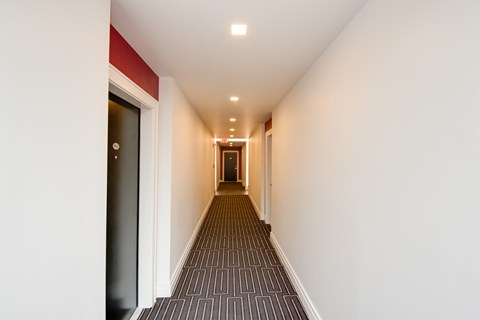A long hallway with a carpeted floor and white walls.