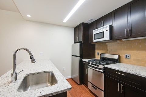 A kitchen with a sink, stove, and refrigerator.