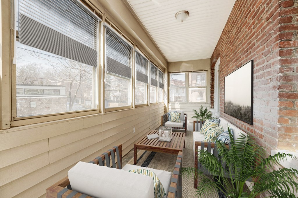 the porch of a home with furniture and a brick wall