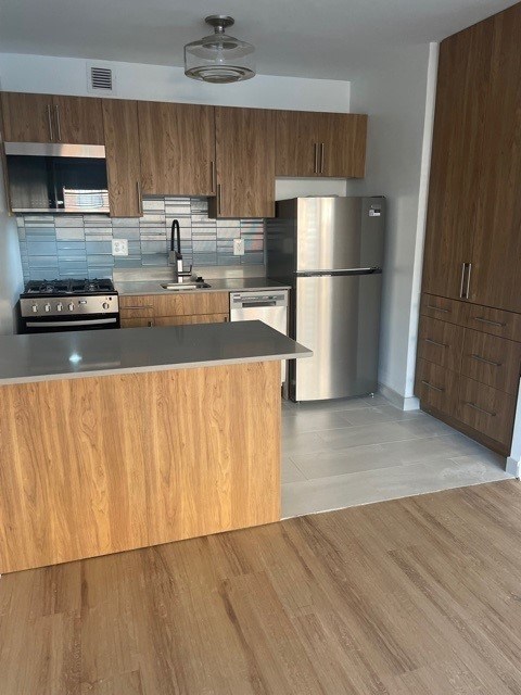 A kitchen with wooden cabinets and a stainless steel refrigerator. at 2400 Pennsylvania Avenue Apartments, Washington, DC,20037