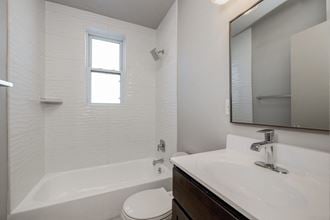 full bathroom with tub sink and mirror at the district flats apartments