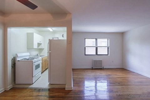 A kitchen with white appliances and wooden floors.