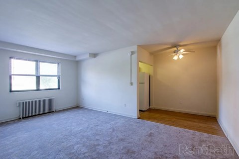 A spacious room with a window and a ceiling fan.