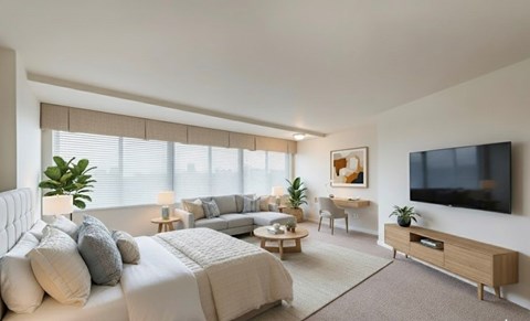 A modern bedroom with a large bed, a flat-screen TV, and a window with blinds.