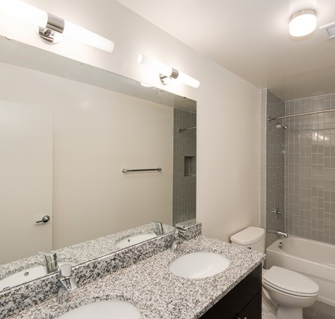 A bathroom with a granite countertop and a white toilet.