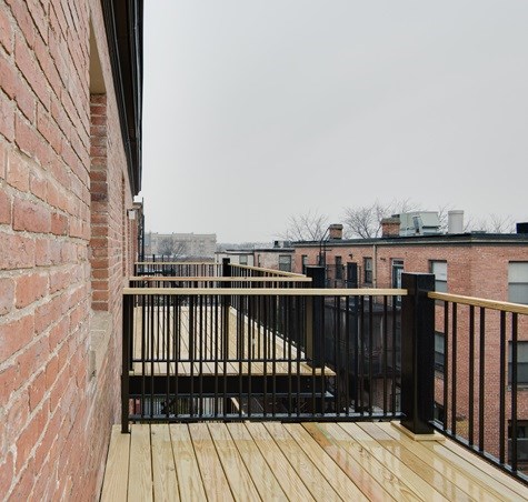 A balcony with a black railing and wooden floor.