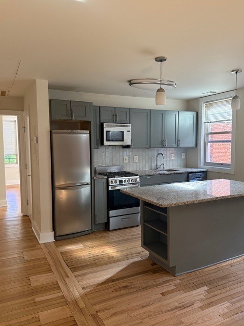 A kitchen with a refrigerator, microwave, oven, and sink.