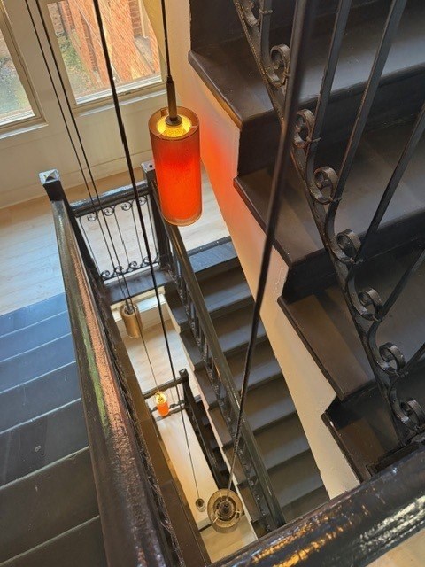 Staircase looking down from the top floor with black railing and pendant lights