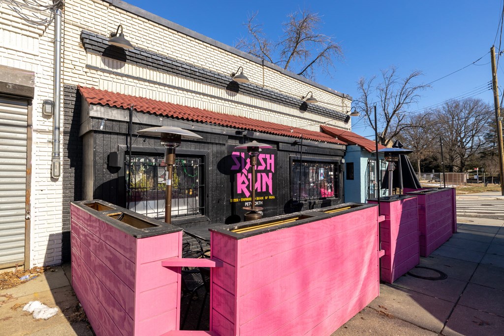 the outside of a pink bar in front of a white building