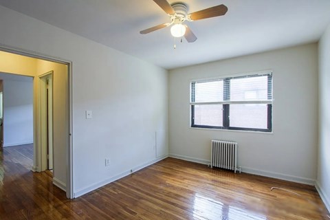 A room with a ceiling fan and a window with blinds.