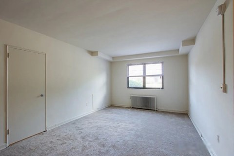 A room with a window and a radiator on the floor.