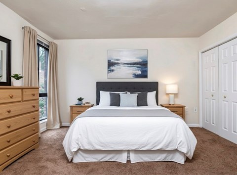 A bedroom with a large bed and a painting above it.