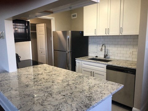 A kitchen with granite countertops and white cabinets.