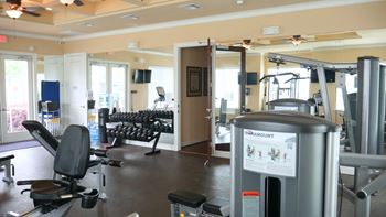 A gym with a variety of equipment including a treadmill and weights.