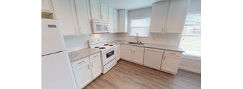A white kitchen with wooden floors and white appliances.