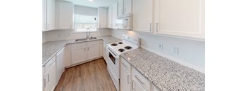 A kitchen with white cabinets and a granite countertop.