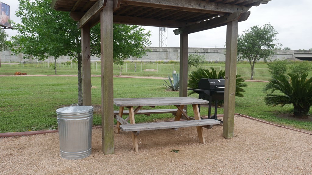 A wooden picnic table is under a wooden shelter.