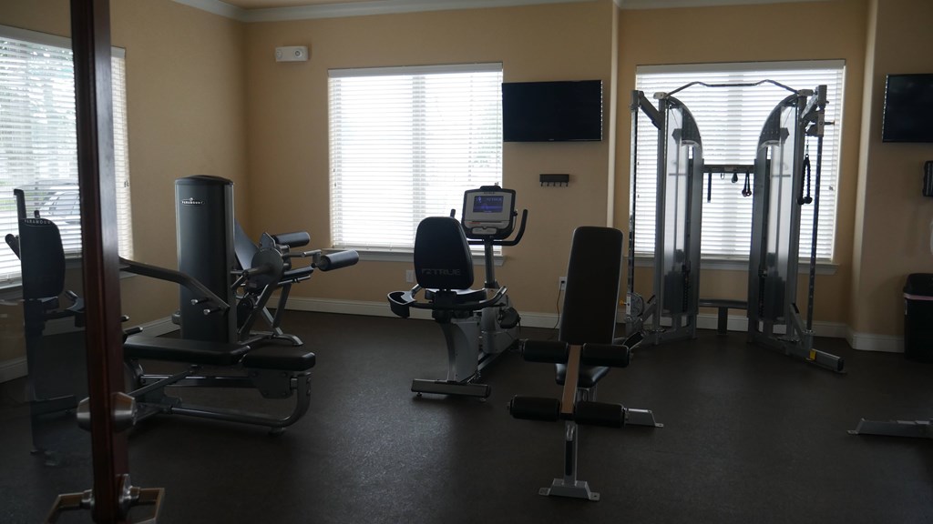 A gym with a variety of equipment including treadmills, weights, and exercise machines.