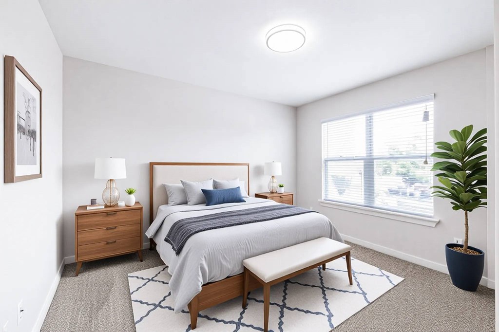 A bedroom with a bed, nightstand, and window.
