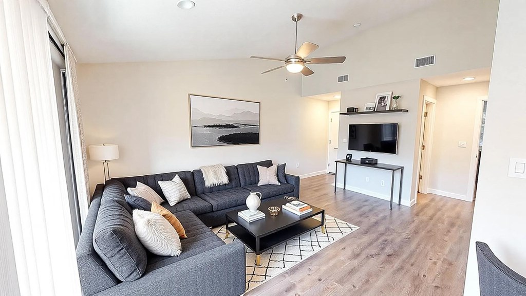 A living room with a grey couch and a painting on the wall.