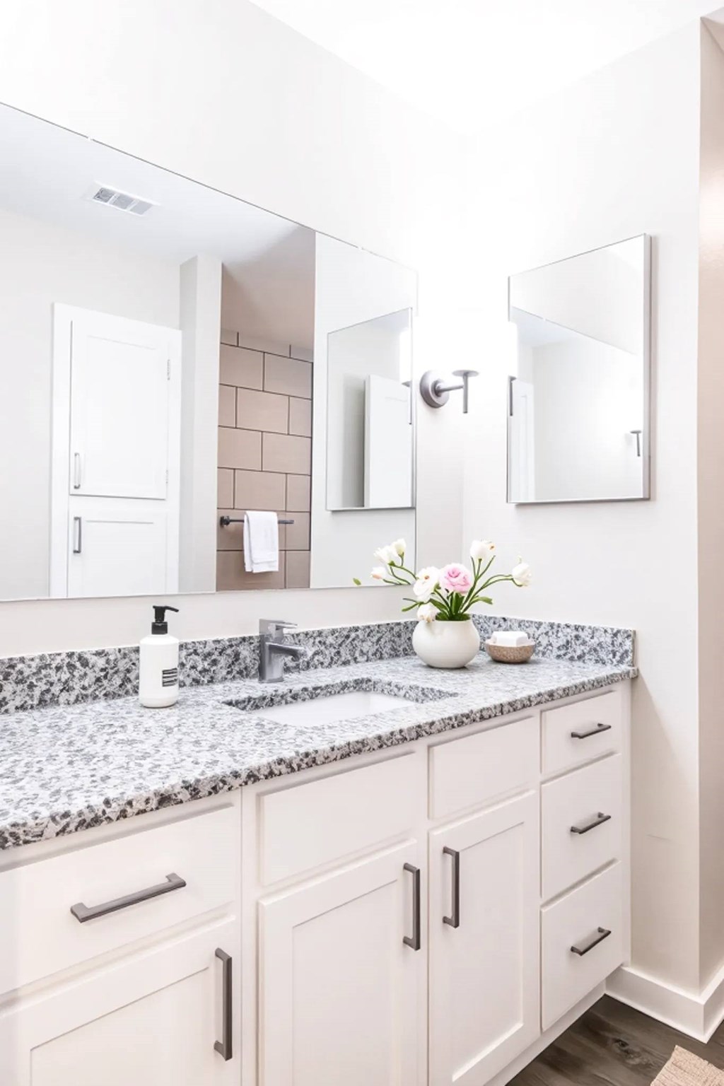 A bathroom with a marble countertop and white cabinets.