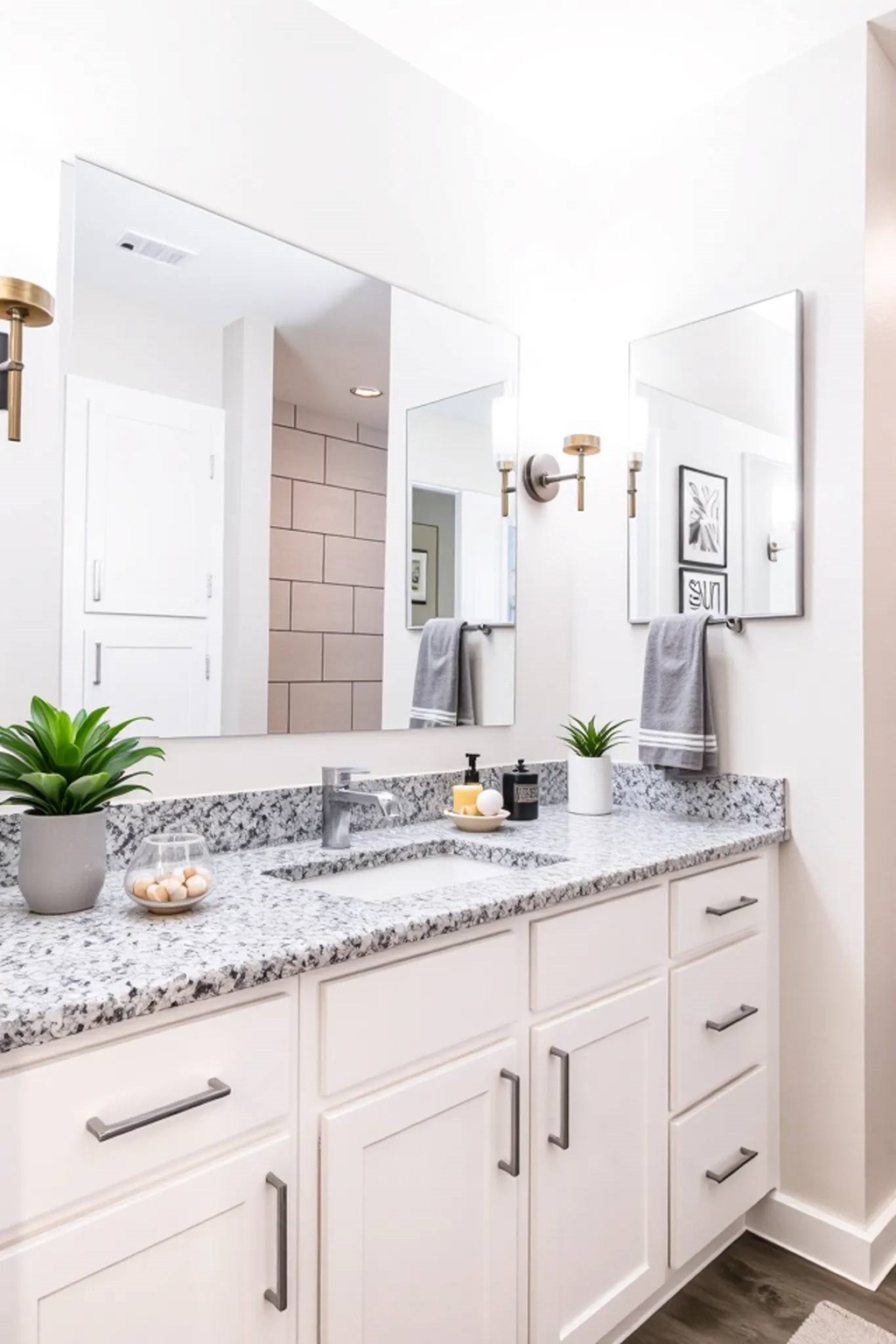 A bathroom with a marble countertop and white cabinets.