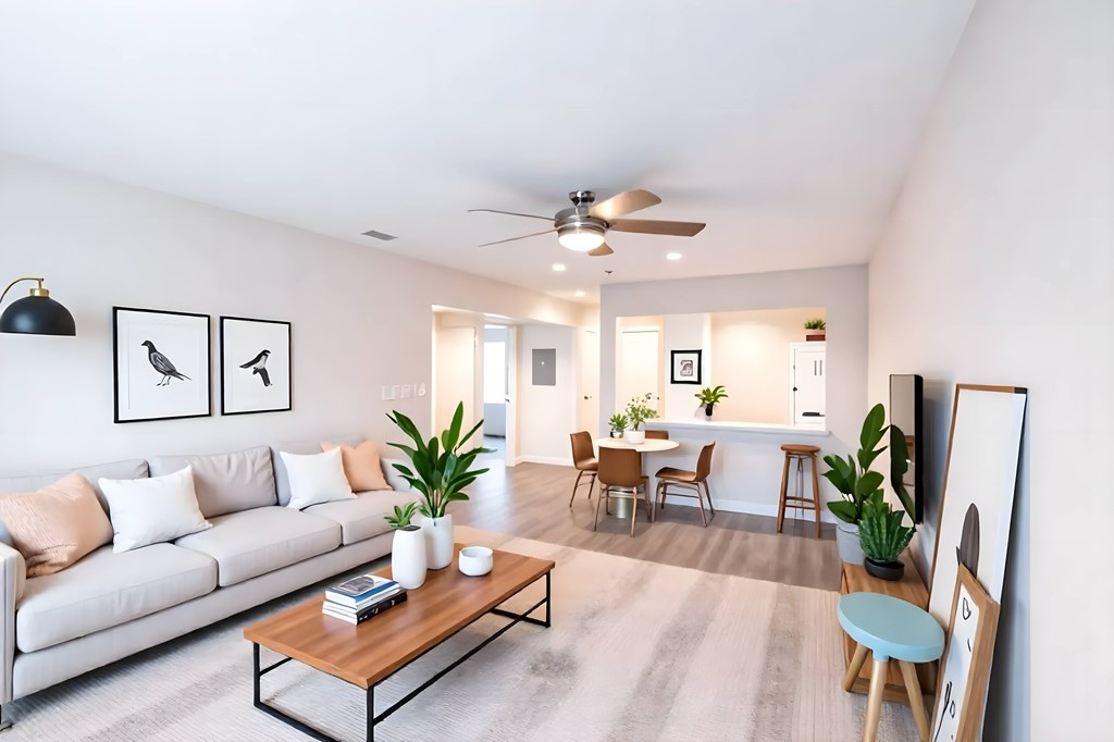 A living room with a white sofa, a wooden coffee table, and a ceiling fan.