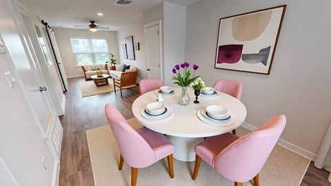 A dining room with a white table and pink chairs.