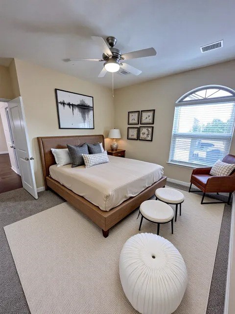 A bedroom with a bed, a chair, and a ceiling fan.