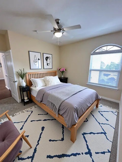 A bedroom with a bed, a chair, and a ceiling fan.