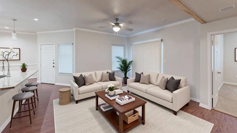 A living room with a white couch, a wooden coffee table, and a bar area.