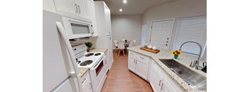 A kitchen with white cabinets and a wooden floor.