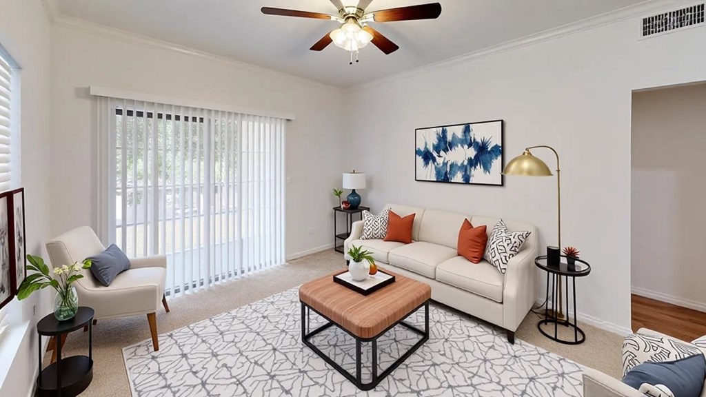 A living room with a white couch, a coffee table, and a ceiling fan.