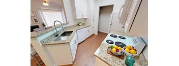 A kitchen with a granite countertop and a bowl of fruit on it.
