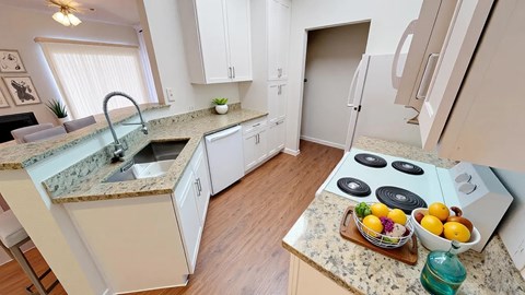 A kitchen with a granite countertop and a bowl of fruit on it.