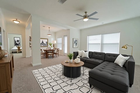 A living room with a black couch, a coffee table, and a ceiling fan.