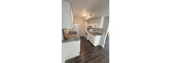 A kitchen with white cabinets and a marble countertop.