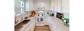 A kitchen with white cabinets and a stove top oven.