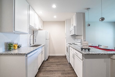 A kitchen with white cabinets and a granite countertop.