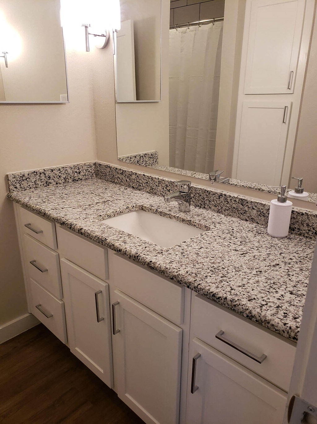 A bathroom with a granite counter top and white cabinets.
