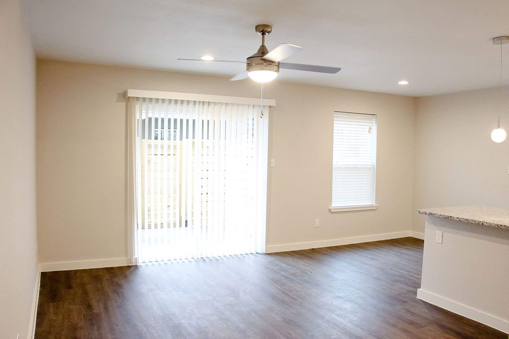 A room with a ceiling fan and a window with blinds.