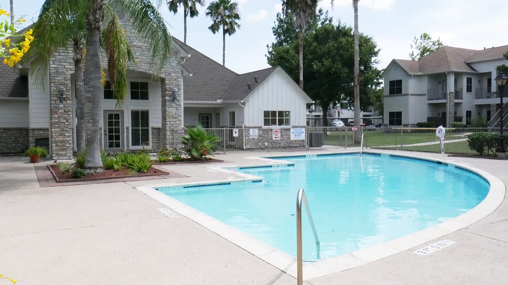 A swimming pool surrounded by palm trees and a white house.