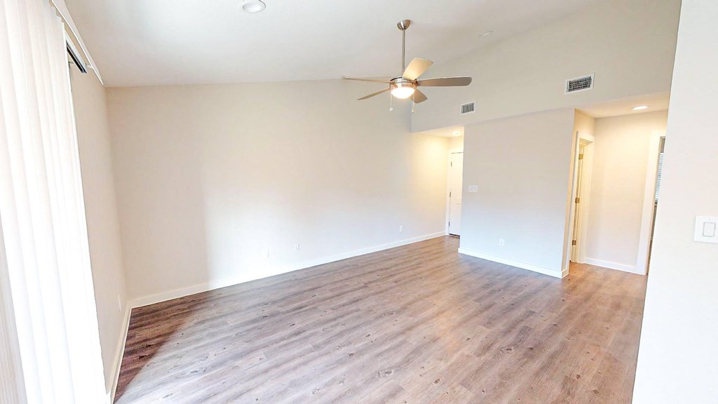 A room with a ceiling fan and wooden flooring.