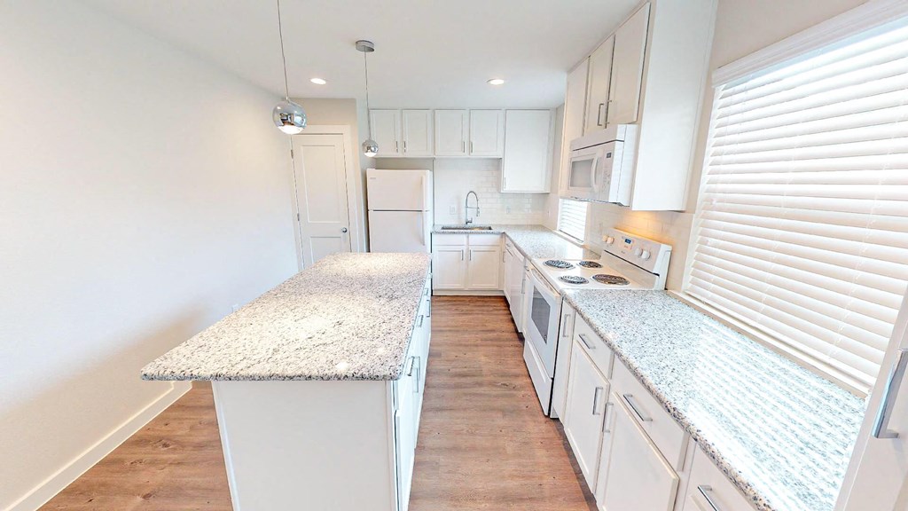 A kitchen with white cabinets and a granite countertop.