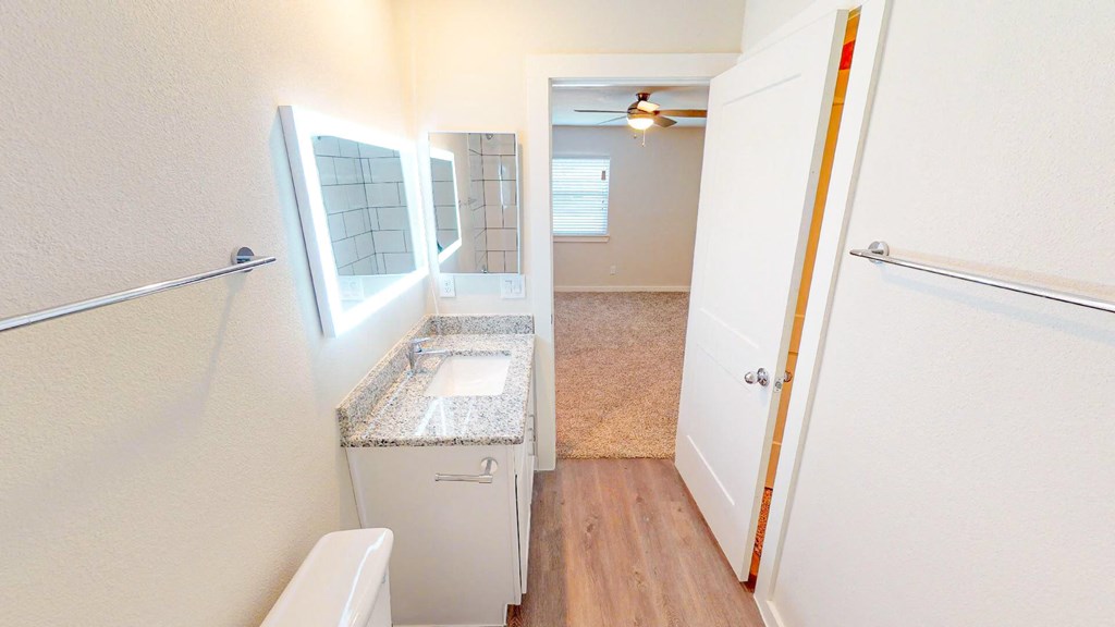 A small bathroom with a toilet, sink, and mirror.