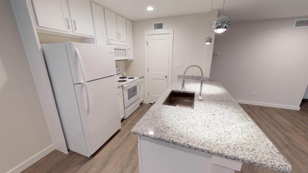 A kitchen with white cabinets and a granite countertop.