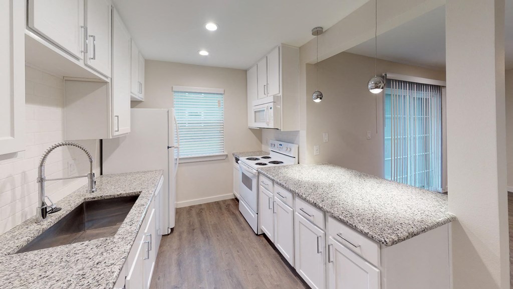 A kitchen with white cabinets and a granite countertop.