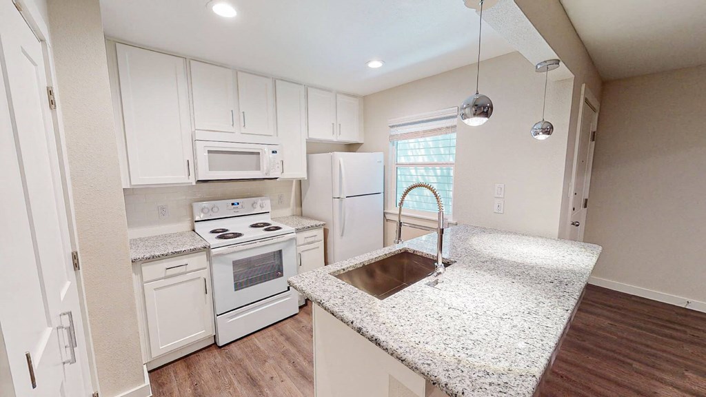 A kitchen with a granite counter top and white cabinets.