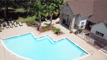 A swimming pool surrounded by a concrete patio and a house.